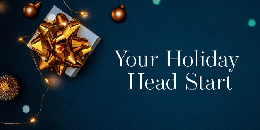 A beautifully wrapped gift against a navy background. At the right, the words: your holiday head start.