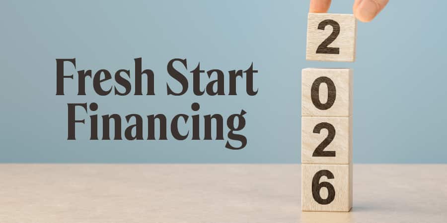 Wooden blocks stacked to display the year 2026, with a hand placing the final block on top against a soft blue background. At the left, the words: fresh start financing.