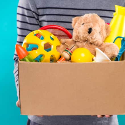A person carrying a cardboard box of toys.