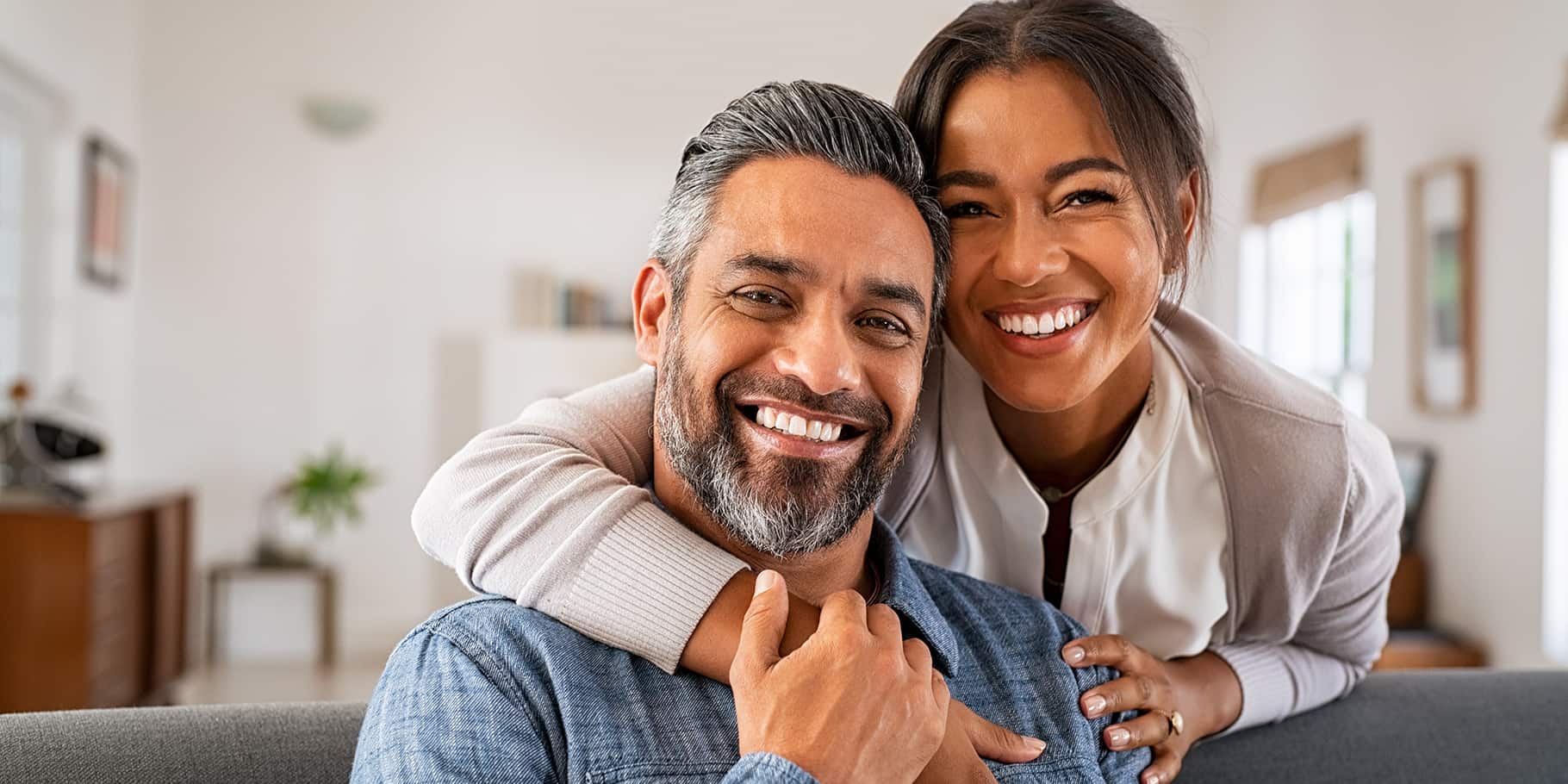 A middle-aged couple smiling and embracing eachother.