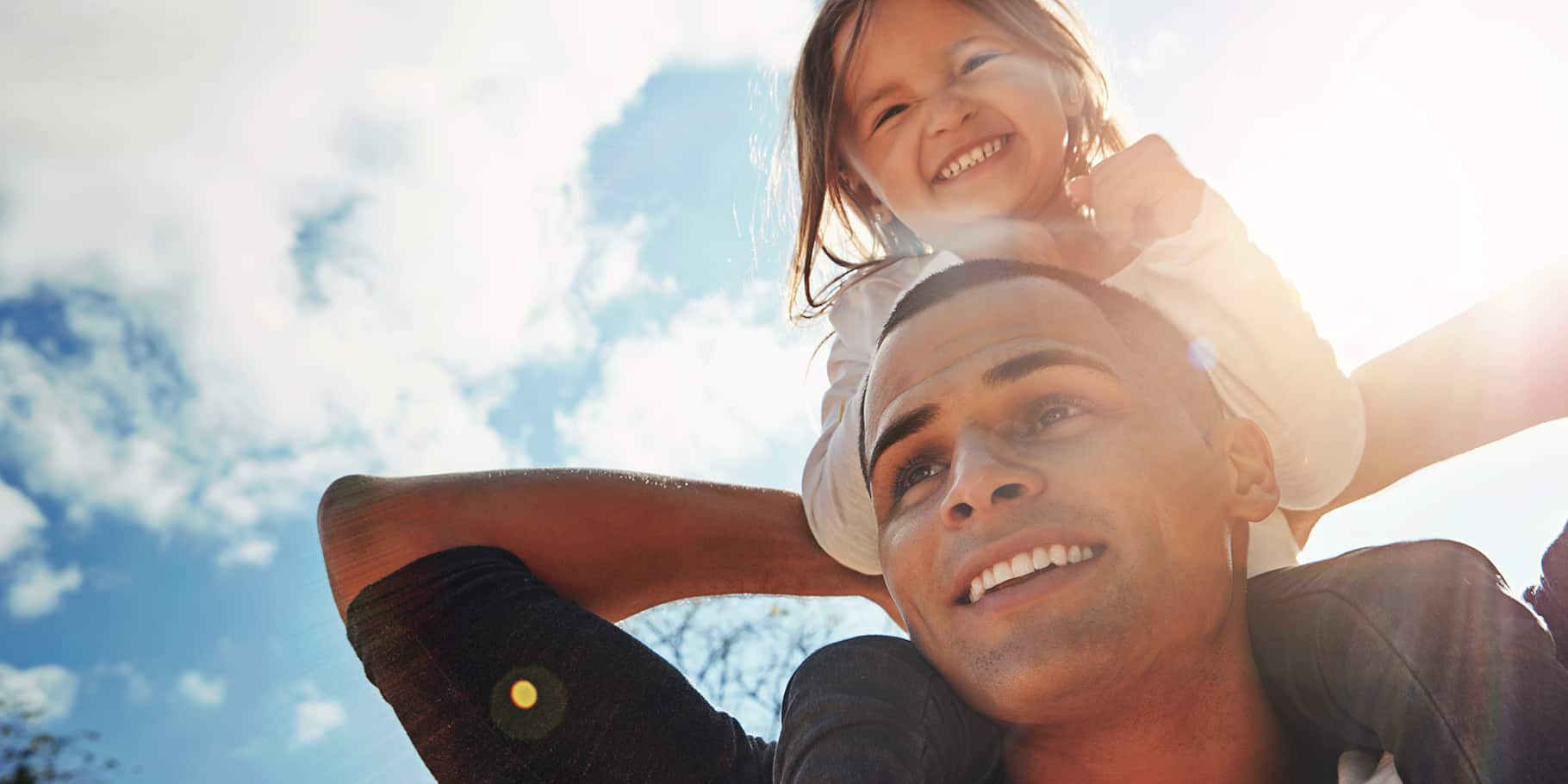 A father carrying his daughter on his shoulders.
