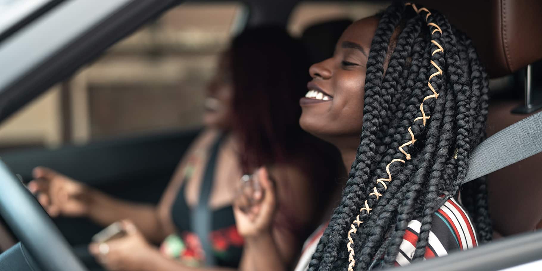 Two smiling women driving in a car.