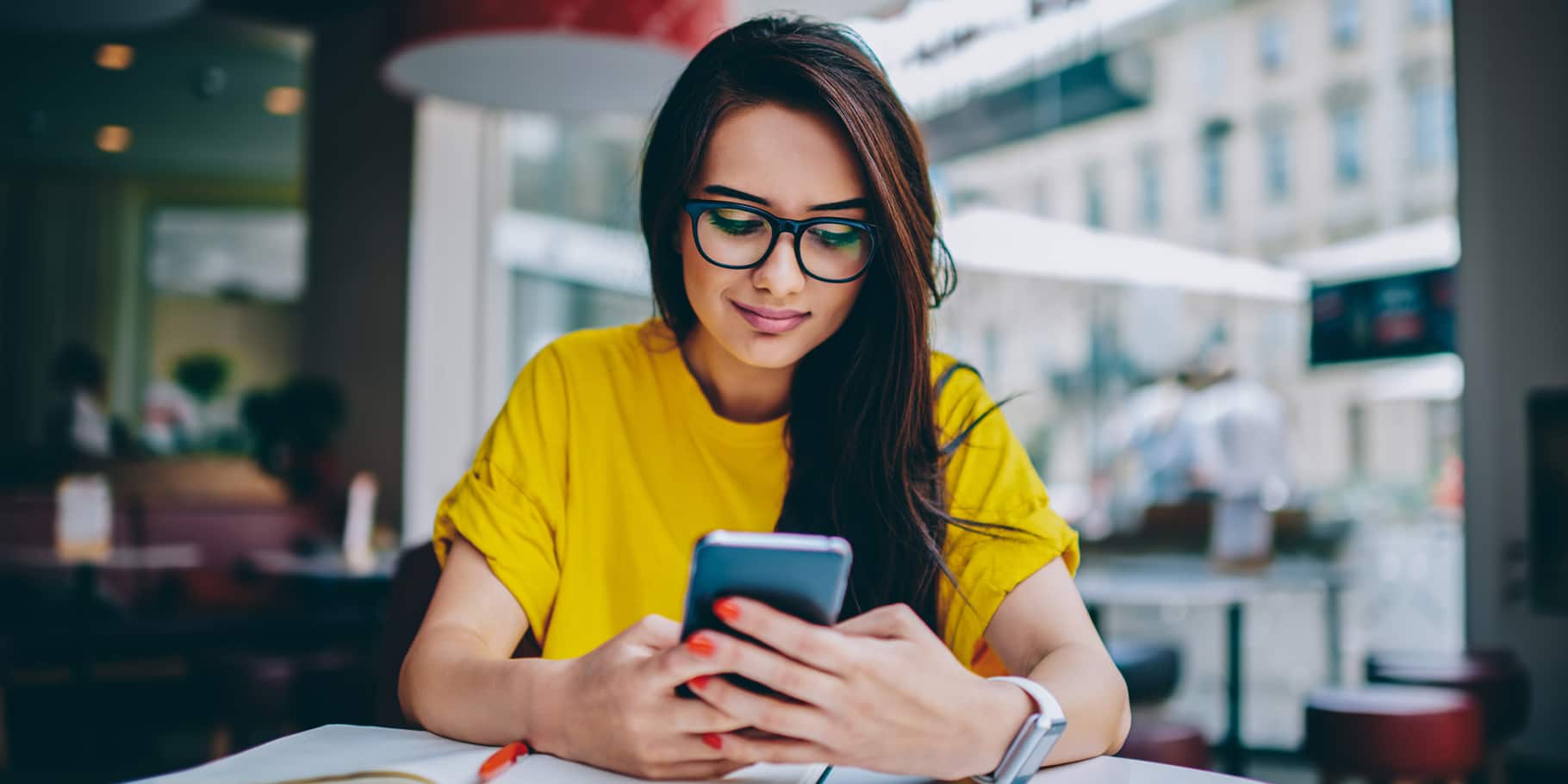 A young woman sitting while using a smartphone.